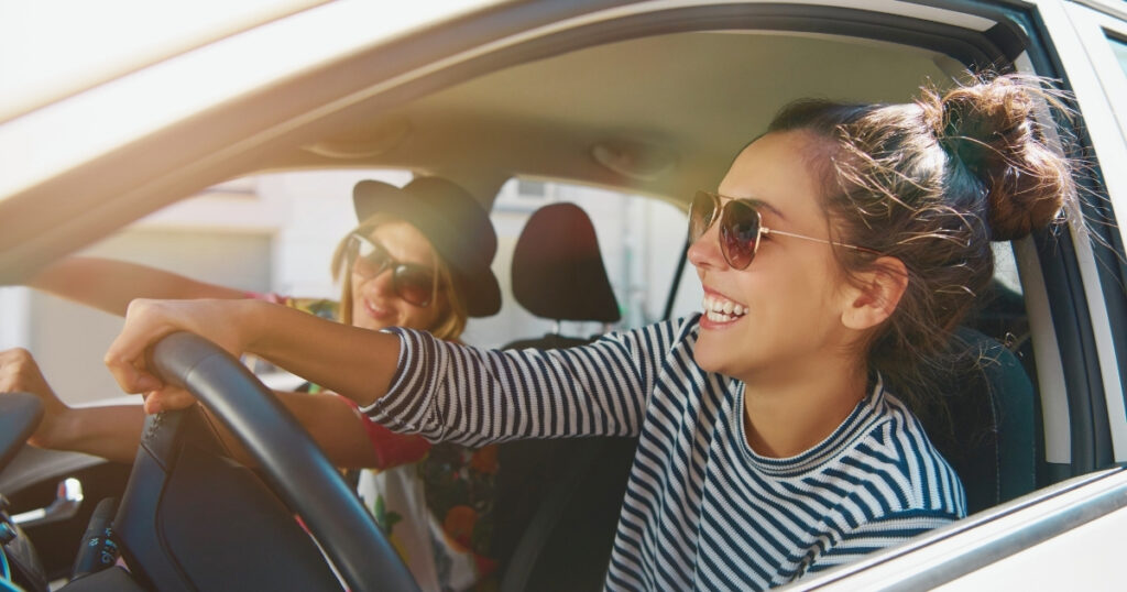 young woman driving with a friend in Canada