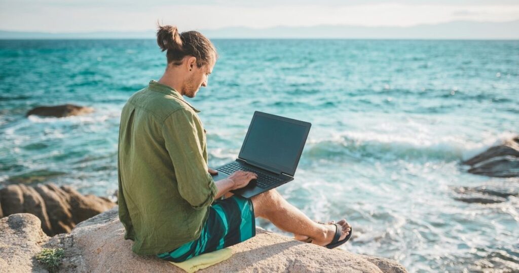 young man using his laptop at the beach