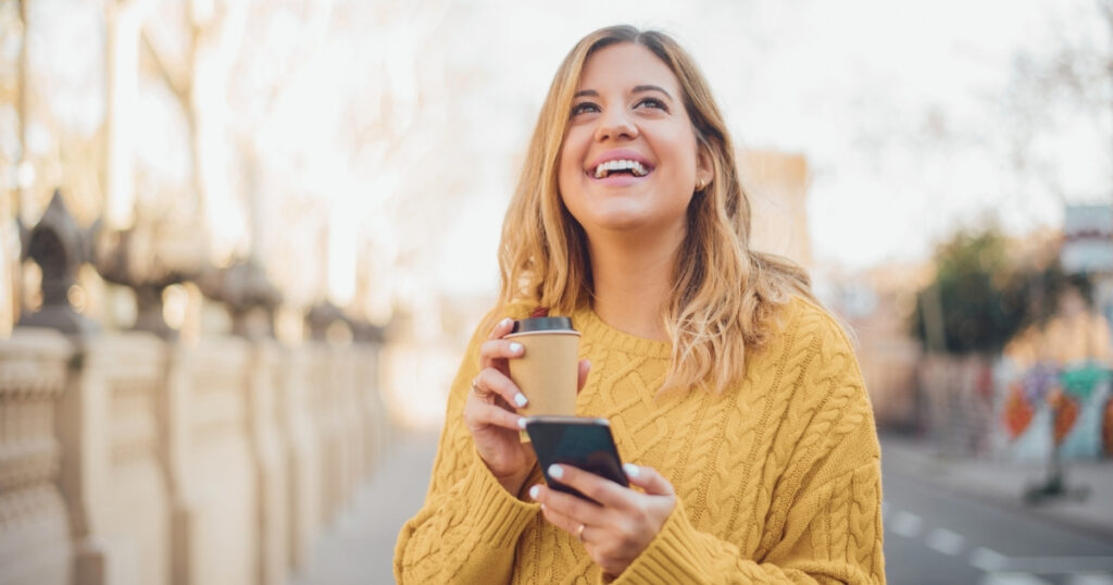 mujer sonriente utilizando internet en su celular con una esim