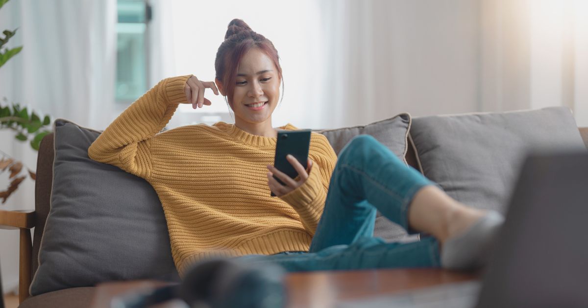 mujer joven sonriente navegando con la esim en su celular