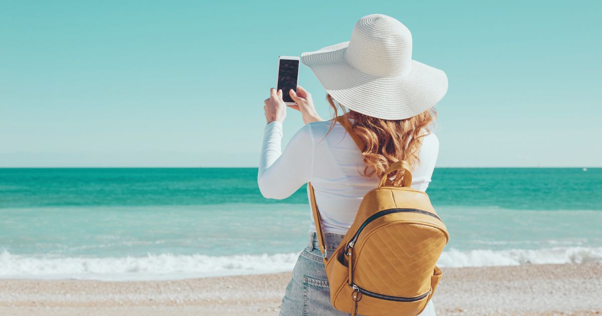 mujer en la playa sacando fotos con su celular