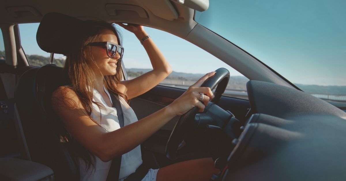 mujer joven sonriente conduciendo coche alquilado en Croacia