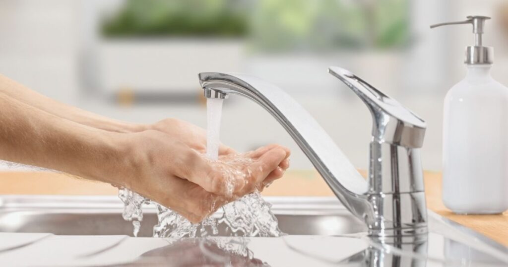 person washing hands with tap water