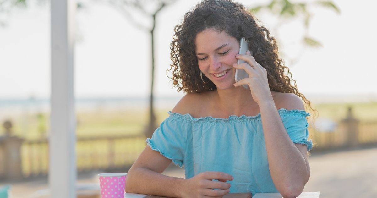 mujer joven sonriente usando internet en su celular con Holasim