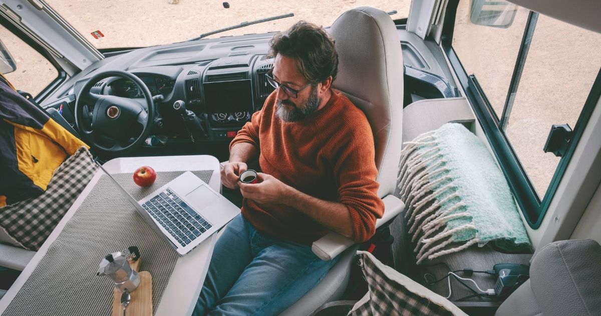 hombre nomada digital trabajando remoto de una caravana